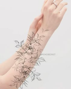 a woman's arm with flowers on it and a hand holding the wrist tattoo