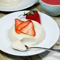 strawberries and yogurt on a white plate with two bowls in the background