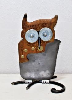 an owl made out of metal and wood sitting on top of a pair of scissors