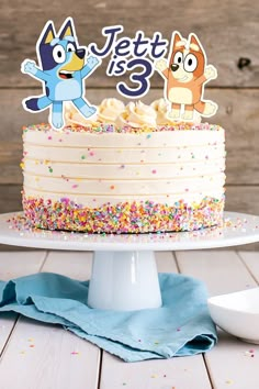 a birthday cake with sprinkles and two cartoon figures on top that says let's 3