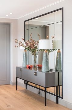 two vases with flowers are sitting on a table in front of a large mirror