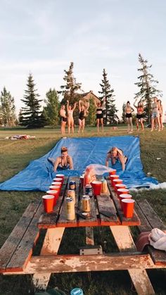 some people are sitting at a picnic table with cups and drinks in front of them