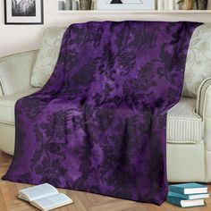 a purple blanket sitting on top of a couch next to a book