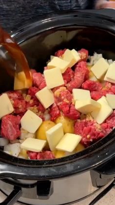 the food is being cooked in the crockpot with meat and cheese on top