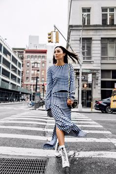 a woman crossing the street wearing a blue and white checkered dress with high heels