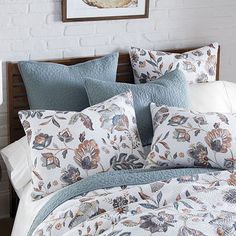 a bed with blue and white comforters in a room next to a brick wall