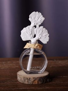 a small glass vase with a white flower in it on top of a wooden table