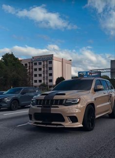 a tan jeep is parked on the side of the road in front of other cars