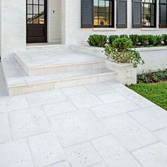 a white house with black shutters on the front door and steps leading up to it