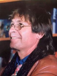 an old photo of a man with glasses and a leather jacket smiling for the camera