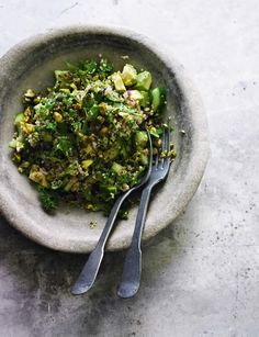 a white bowl filled with food next to two forks