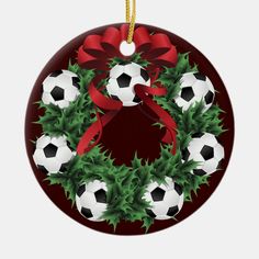 a christmas ornament with soccer balls and holly wreath on the front, hanging from a yellow ribbon