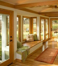 a living room filled with lots of windows and furniture next to a wooden flooring area