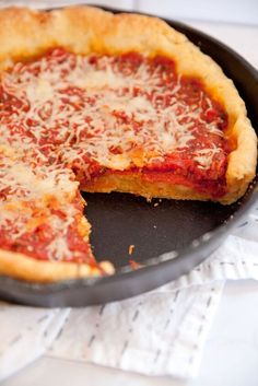 a deep dish pizza with cheese and sauce in a cast iron pan on a table