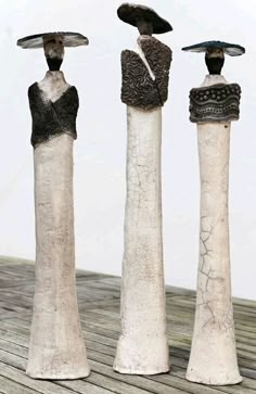 three sculptures made out of clay are standing on a wooden surface and one is holding an umbrella