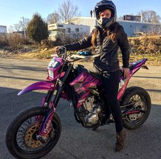 a woman sitting on top of a pink dirt bike