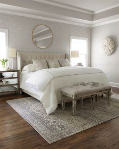 a bedroom with a large bed and white furniture in the corner, along with a mirror on the wall