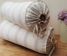 two pillows stacked on top of each other next to a vase with flowers in it