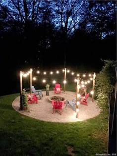 an outdoor fire pit is lit up at night with string lights and lawn chairs around it