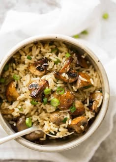 a bowl filled with rice and mushrooms on top of a white napkin next to a spoon