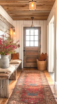 a hallway with a rug, bench and flowers on the floor in front of a door