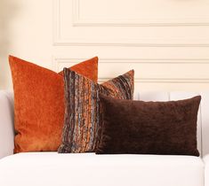 three different colored pillows on a white couch