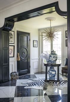 the foyer is decorated in black and white with an elaborate vase on it's stand