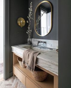 a bathroom with marble counter top and gold mirror