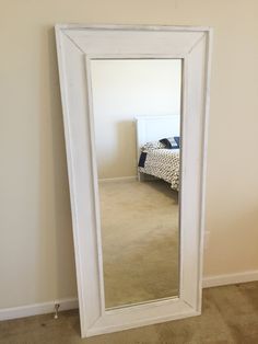 a large white mirror sitting in the corner of a room next to a bed and dresser