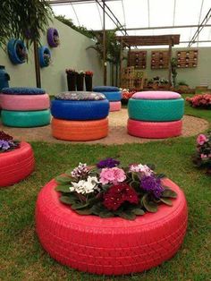 an assortment of colorful tires and flowers on the grass in front of a building with windows