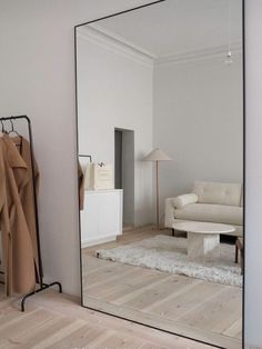 a mirror that is on the wall next to a white couch and coat hanger