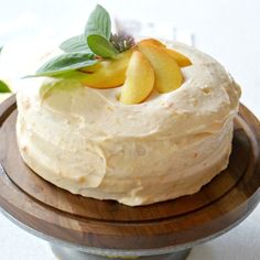 a close up of a cake on a wooden platter with leaves and apples on top