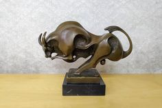 a bronze statue of a running bull on a wooden table