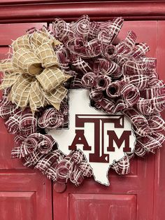 the texas a & m wreath is hanging on a red door with burlock