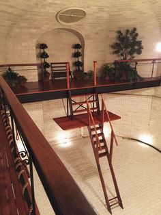 an indoor swimming pool with stairs leading up to the second floor and potted plants on either side