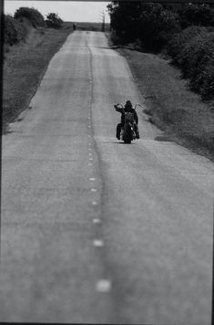 a person riding a motorcycle down the middle of a road