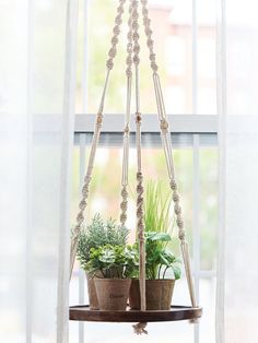 two potted plants are hanging from a window sill in front of a white curtain