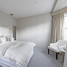 a large white bed sitting in a bedroom next to a window