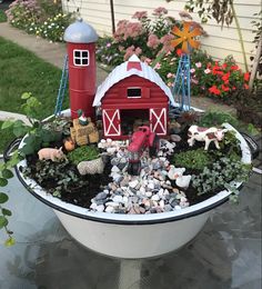 a bowl filled with rocks and plants on top of a table next to a house