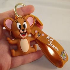 a hand holding a key chain with a cartoon mouse on it's side and a name tag attached to it