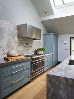 a kitchen with blue cabinets and marble counter tops, an oven and sink are in the center