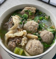 a white bowl filled with soup and meatballs