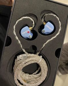 an open box with two ear buds and wires in the inside one is blue, while the other is white