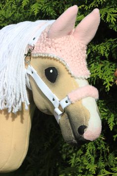 a stuffed horse with a pink hat on it's head next to some trees