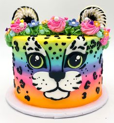 a multicolored cake decorated with an animal's face and flowers on top