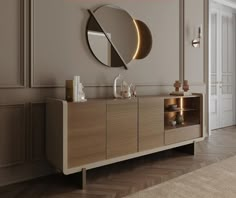 a large mirror on the wall above a wooden cabinet in a room with beige walls and wood flooring