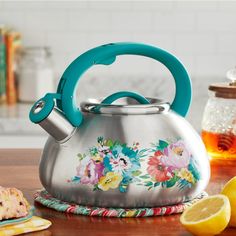 a tea kettle sitting on top of a wooden table next to lemons and honey