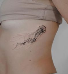 a woman's stomach with a jellyfish tattoo on it