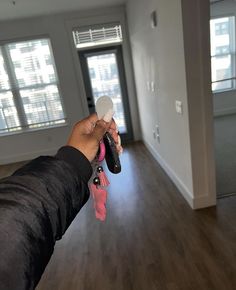 a hand holding a remote control in an empty room with hard wood floors and windows