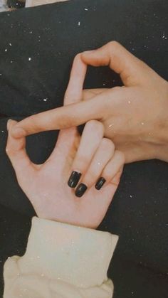 two hands with black manicures making the v sign